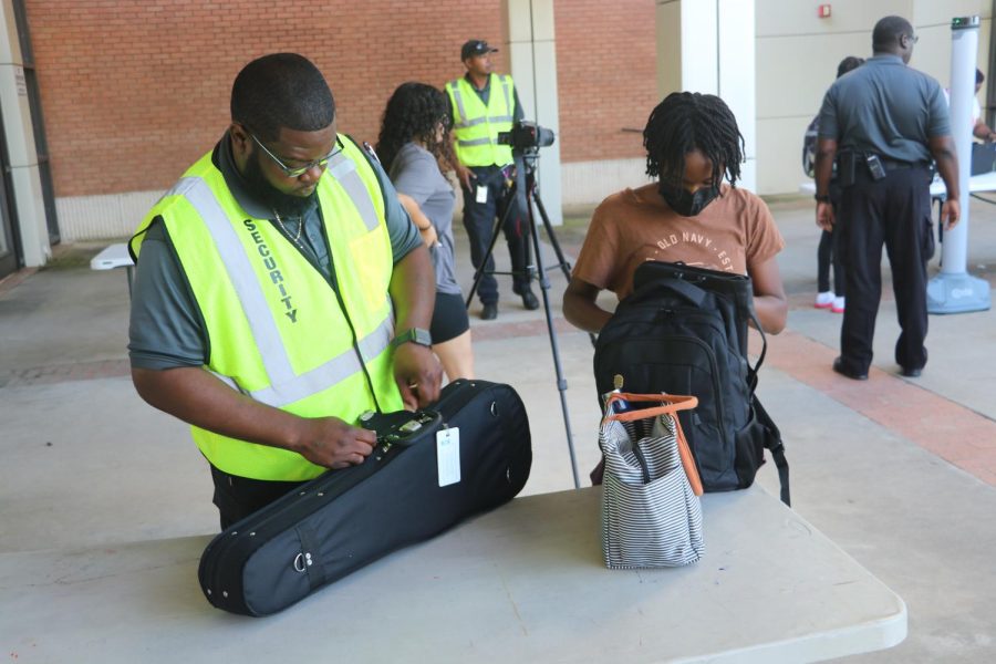 Security officer helps put back together a students belongings after it was checked. 