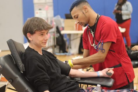 Left, senior Jackson Betette distracts himself as a Red Cross worker injects the needle to withdraw blood. He was one of many students to sit in the donator chairs this past Thursday. 