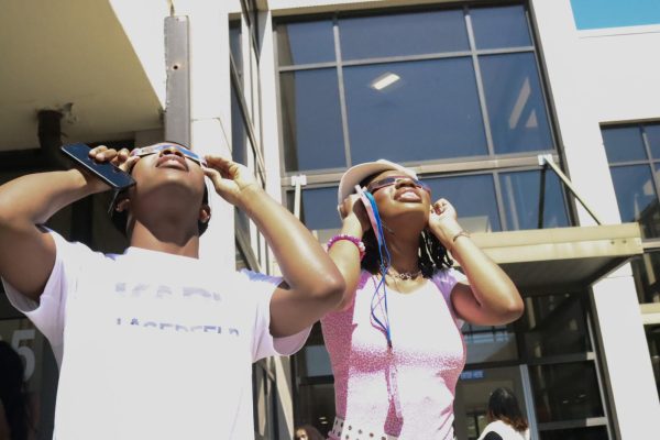 Sophomores Dante Green and Karinne Alleyne watch the solar eclipse in the Shakespeare Garden. The pair borrowed glasses from other students.