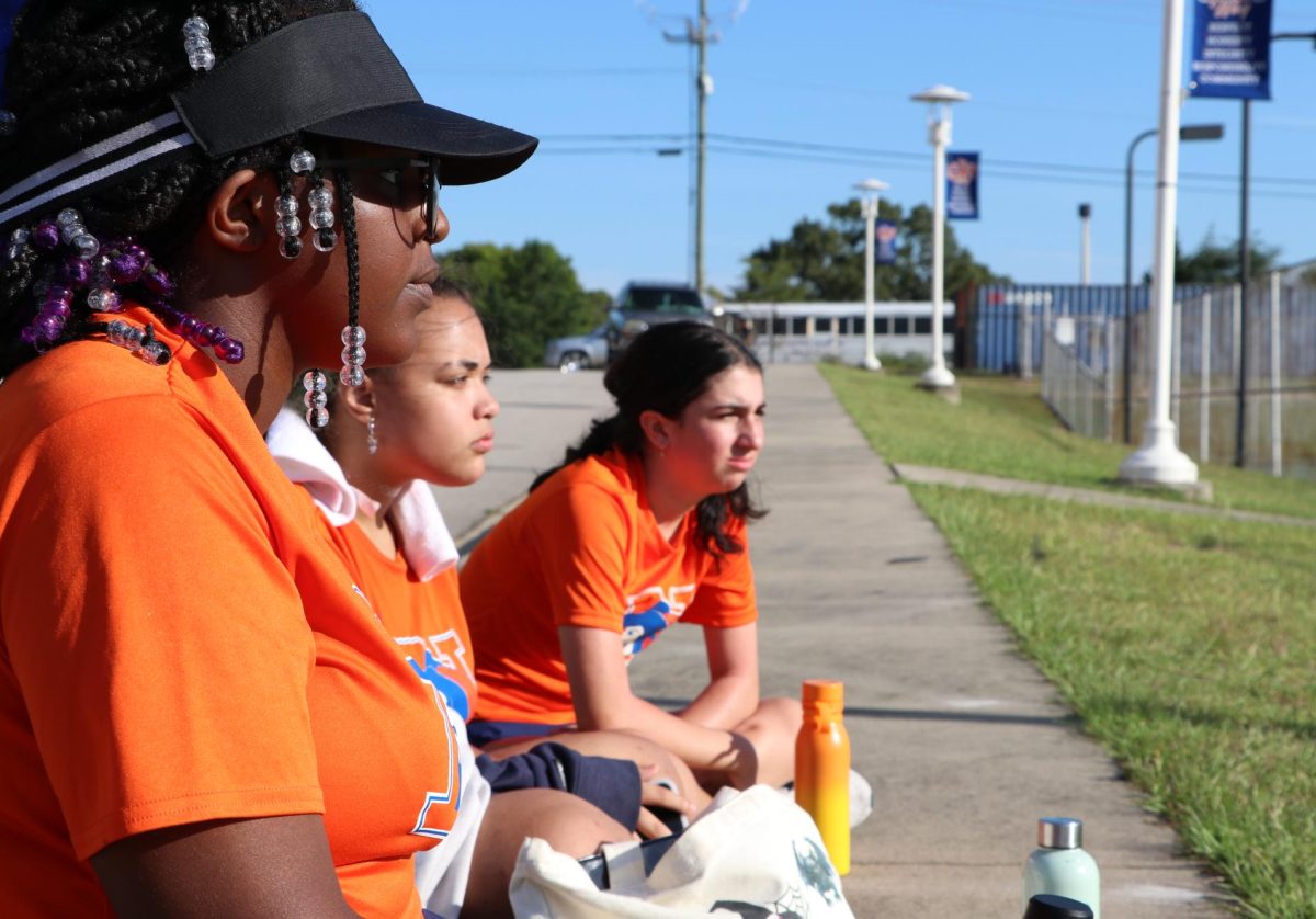 Three members of the girls tennis team watch their teammates.