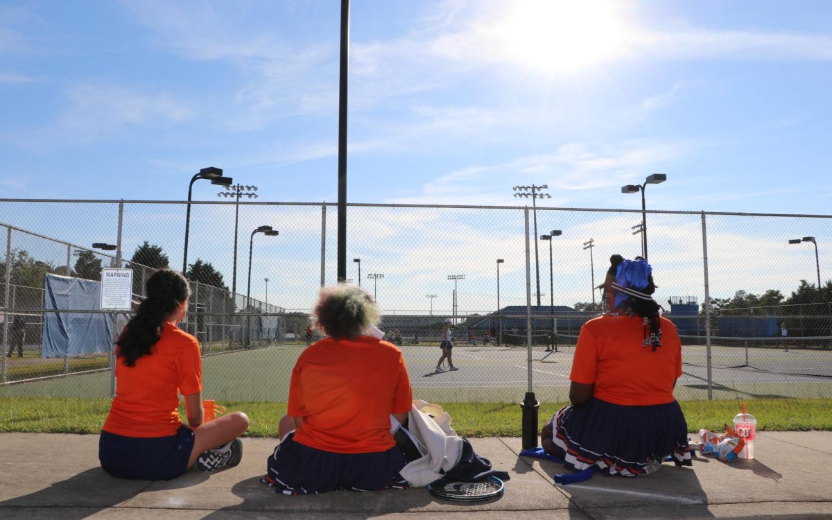 Three members of the girls tennis team watch their teammates play.