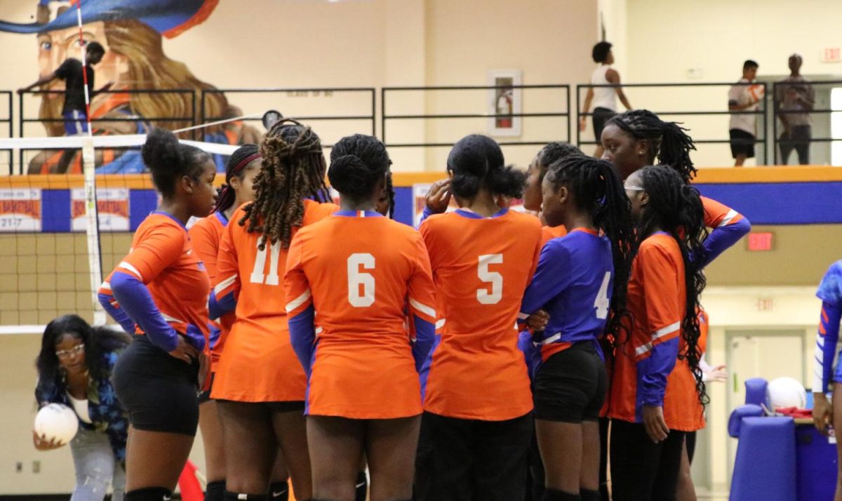 Junior varsity girls volleyball team huddles together.