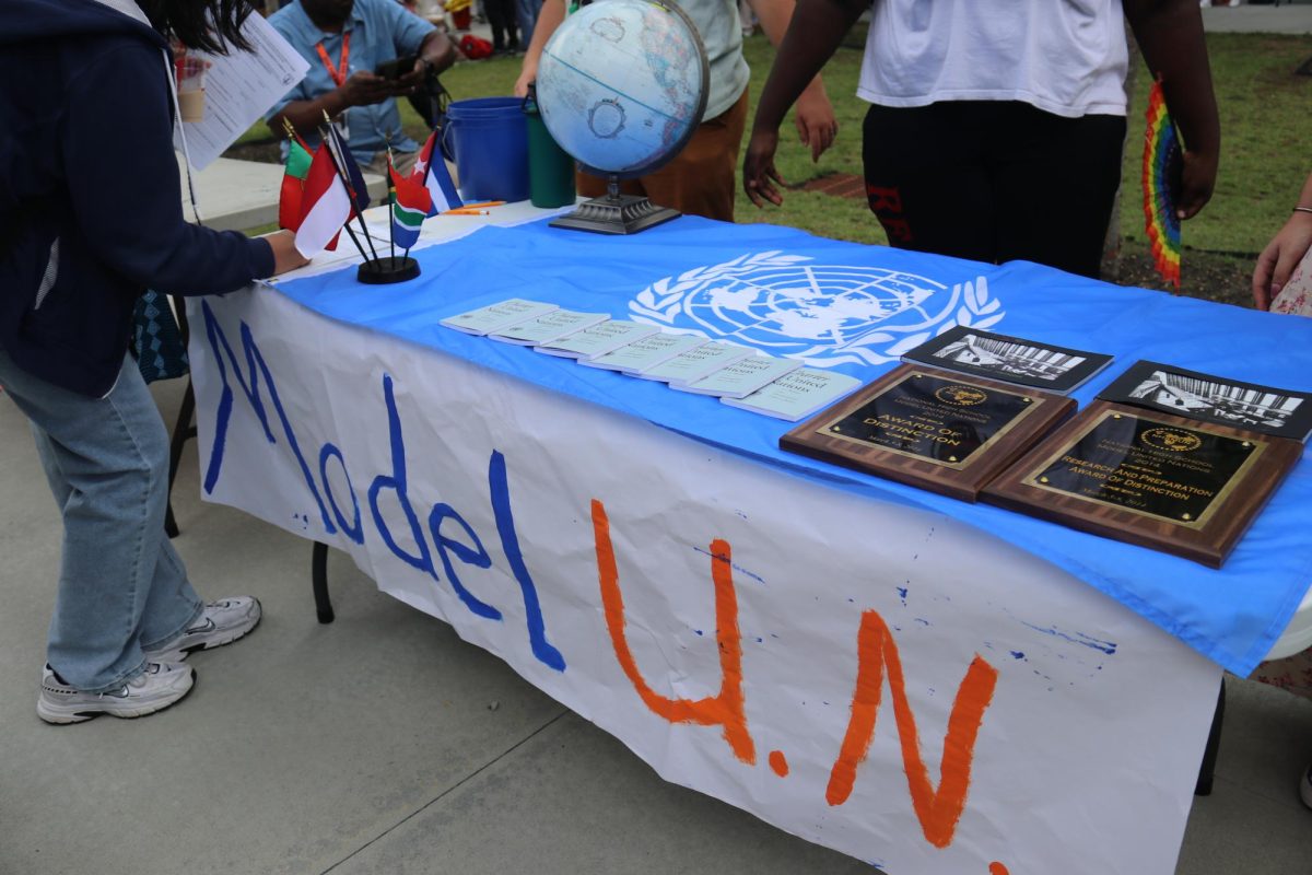 Model UN decorated a table to showcase its value. Achievement plaques, a globe and a flag from different countries were on top of the table.

