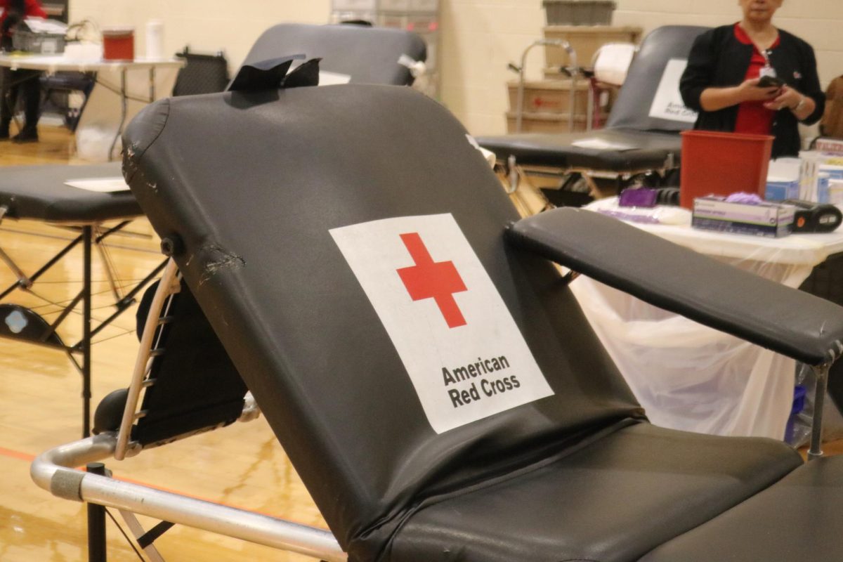 A donor sits in a folded chair during their blood donation. An American Red Cross professional cleans the chair after each use. 
