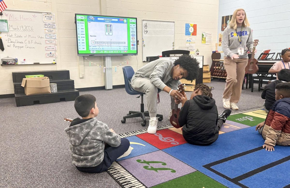 Senior Caden Holman shows Conder Elementary students how to use a guitar.